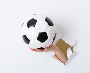 Image showing Soccer ball hold with woman hand break through the paper wall