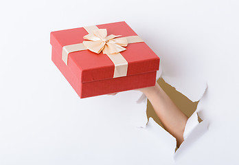 Image showing Hand hold with present box break through the paper wall