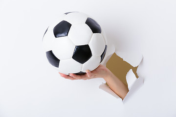 Image showing Hand holding soccer ball through the paper hole 