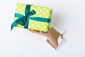 Image showing Hand break through paper with green present box