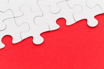 Image showing White paper jigsaw puzzles over red background