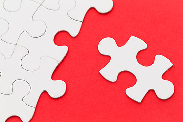 Image showing Incomplete white puzzle with red color background with copyspace