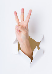 Image showing Three finger breaking through paper wall