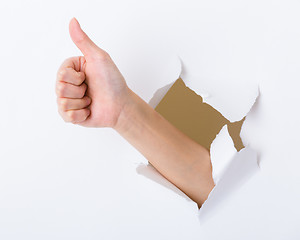 Image showing Hand with thumb up through a hole in paper