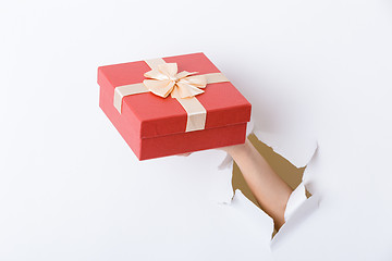 Image showing Hand holding giftbox through the hole in paper