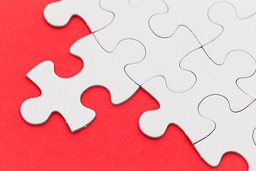 Image showing Plain white jigsaw puzzle on red background