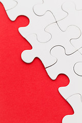 Image showing Blank white jigsaw puzzles on a bright red paper background