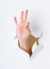 Image showing Finger showing ok sign bursting through paper