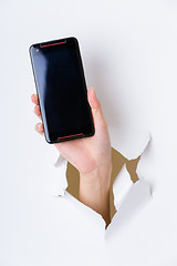 Image showing Hand break through paper and hold with blank screen of cellphone