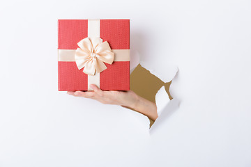 Image showing Hand break through paper with red present box