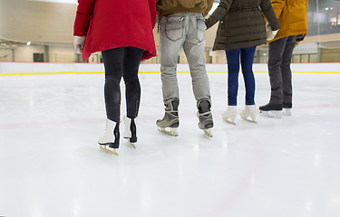 Image showing close up of happy friends skating on ice rink