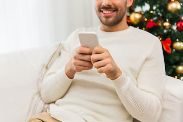 Image showing smiling man with smartphone at home for christmas