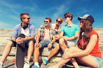 Image showing group of smiling friends sitting on city street