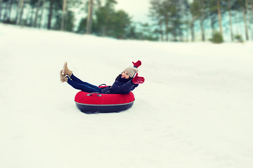 Image showing happy teenage girl sliding down on snow tube