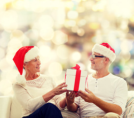 Image showing happy senior couple in santa hats with gift box