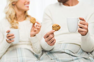 Image showing close up of happy couple with cookies and tea cups