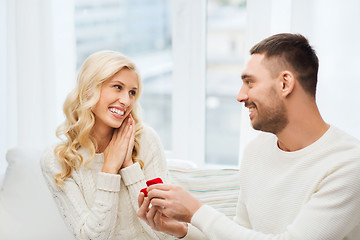 Image showing happy man giving engagement ring to woman at home