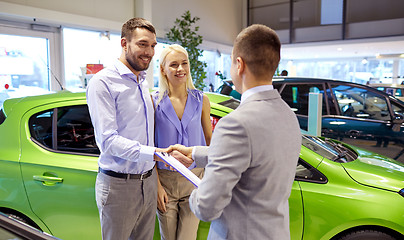 Image showing happy couple with car dealer in auto show or salon