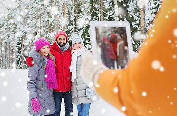 Image showing smiling friends with tablet pc in winter forest