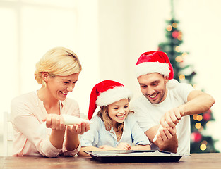 Image showing happy family in santa helper hats making cookies