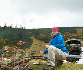 Image showing hiking man prepare tasty sausages on campfire