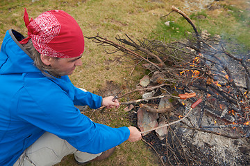 Image showing hiking man prepare tasty sausages on campfire