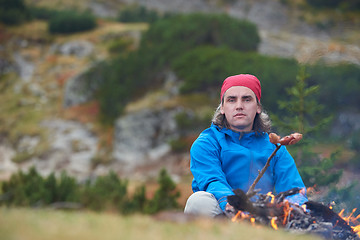 Image showing hiking man prepare tasty sausages on campfire