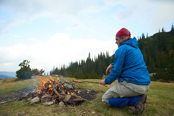 Image showing hiking man prepare tasty sausages on campfire