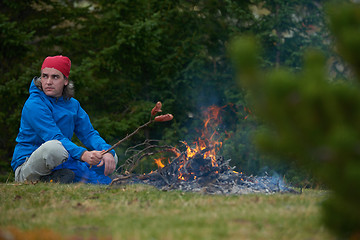 Image showing hiking man prepare tasty sausages on campfire