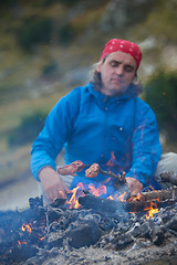 Image showing hiking man prepare tasty sausages on campfire