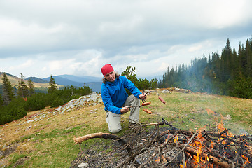 Image showing hiking man prepare tasty sausages on campfire