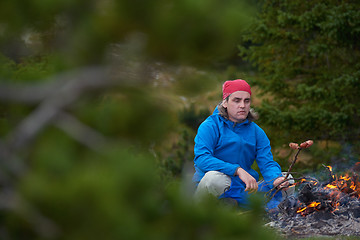 Image showing hiking man prepare tasty sausages on campfire