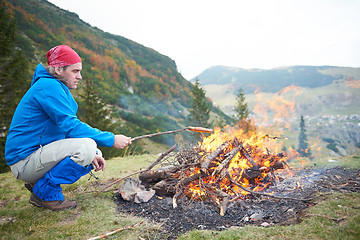 Image showing hiking man prepare tasty sausages on campfire