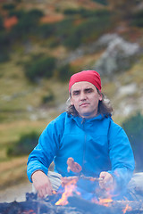 Image showing hiking man prepare tasty sausages on campfire