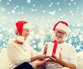 Image showing happy senior couple in santa hats with gift box