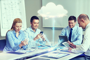 Image showing smiling business people with gadgets in office