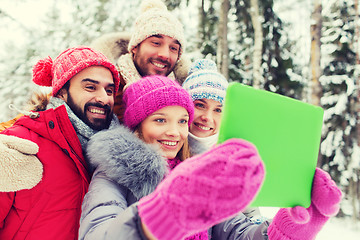 Image showing smiling friends with tablet pc in winter forest