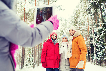 Image showing smiling friends with tablet pc in winter forest