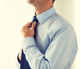 Image showing close up of man in shirt adjusting tie on neck