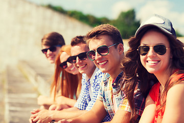 Image showing close up of smiling friends sitting on city street