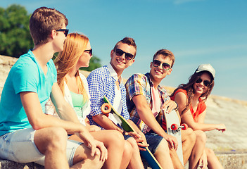 Image showing group of smiling friends sitting on city street