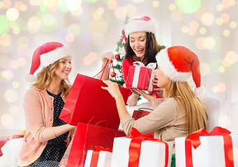 Image showing happy women in santa hats with christmas gifts