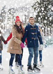 Image showing happy friends ice skating on rink outdoors