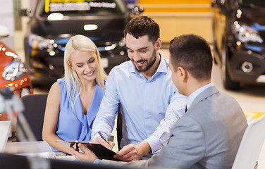 Image showing happy couple with car dealer in auto show or salon