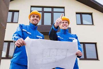 Image showing smiling builders with blueprint pointing finger