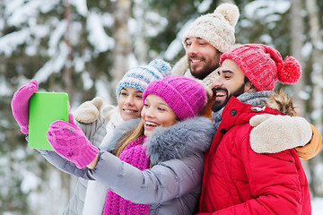 Image showing smiling friends with tablet pc in winter forest