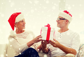 Image showing happy senior couple in santa hats with gift box