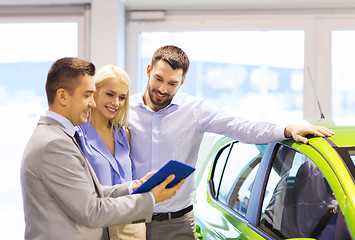 Image showing happy couple with car dealer in auto show or salon