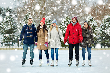 Image showing happy friends ice skating on rink outdoors