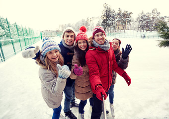 Image showing happy friends with smartphone on ice skating rink